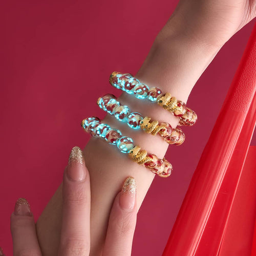 Golden Snake Firefly Glass Swirl Bracelets with glowing red and gold beads and 18k gold-plated snake charm stacked on wrist by NOGU